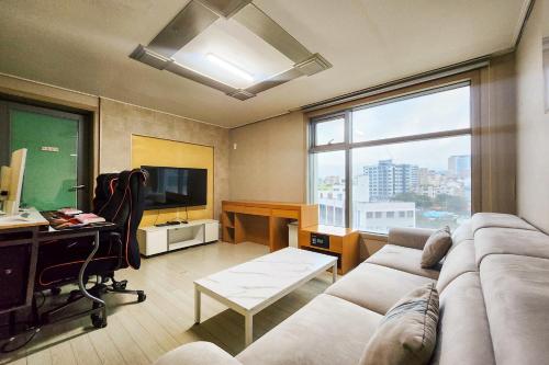a living room with a couch and a desk and a window at Joy Hotel in Jeju