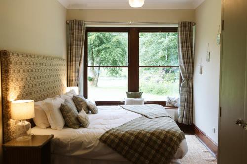a bedroom with a bed and a large window at The Coach House in Castle Douglas