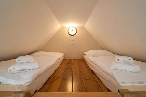 two beds in a room with a clock on the wall at Pension Slunečnice & Panorama Restaurace Farma in Špindlerův Mlýn