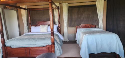 two twin beds in a bedroom with two posts at The Lantern Gardens - Oloirien in Kiserian
