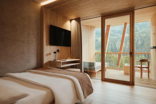 a bedroom with a bed and a large window at Taubers Bio Vitalhotel in Chienes