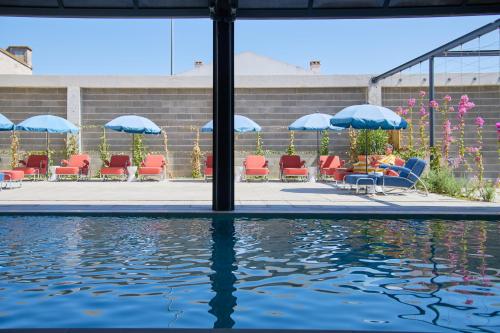 a pool with chairs and umbrellas next to the water at Moagem Industrial Lodge in Viana do Alentejo