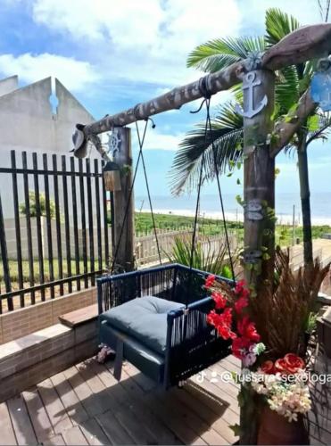 um baloiço num alpendre com o oceano ao fundo em Quarto frente mar com sacada! em Barra Velha