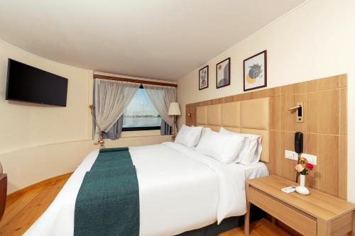 a hotel room with a large bed and a television at Shepherd I Dahabya in Esna