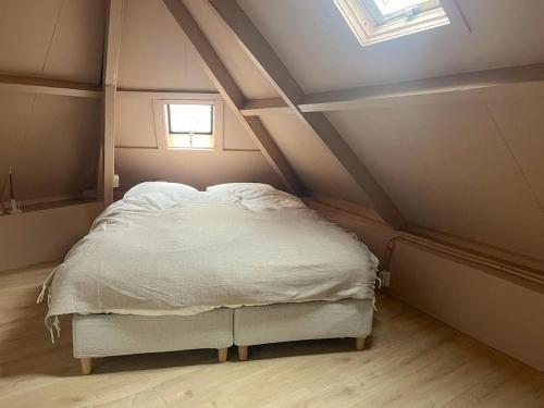 a bed in a room with a roof with a window at Cozy apartment in Enschede