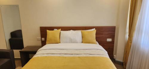a bedroom with a bed with yellow and white pillows at The Lantern Gardens - Oloirien in Kiserian