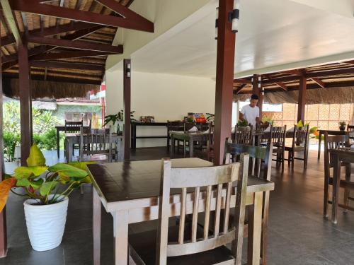 a restaurant with tables and chairs and a man in the background at The Ananyana Beach Resort by SMS Hospitality in Panglao