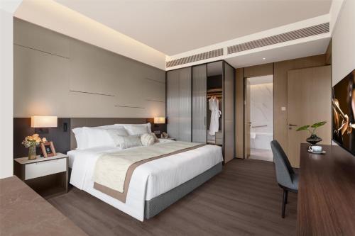a bedroom with a large bed and a desk and a chair at Ascott Fengyishan Shenzhen in Shenzhen