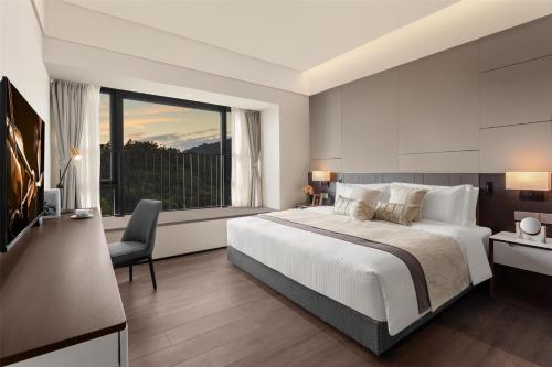a bedroom with a large bed and a large window at Ascott Fengyishan Shenzhen in Shenzhen