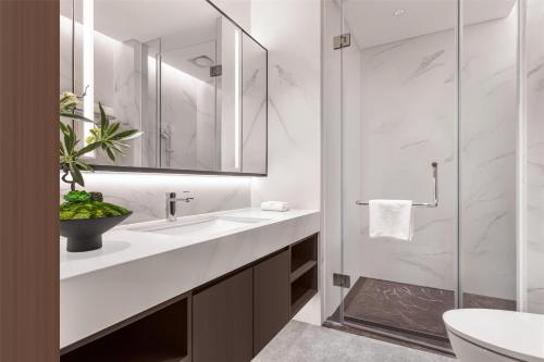 a white bathroom with a sink and a shower at Ascott Fengyishan Shenzhen in Shenzhen