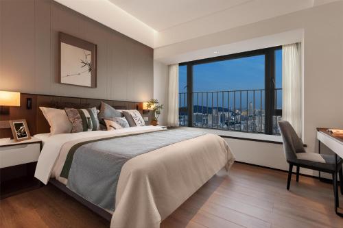 a bedroom with a large bed and a large window at Ascott Fengyishan Shenzhen in Shenzhen
