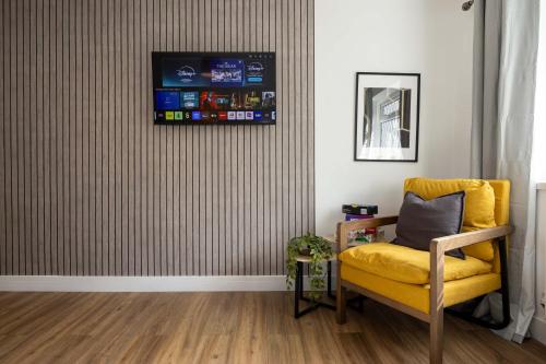 a yellow chair in a room with a striped wall at Spacious Apartment near MCR Airport in Wythenshawe