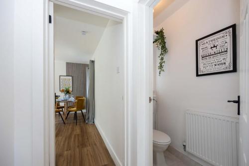 a white hallway with a toilet and a table at Spacious Apartment near MCR Airport in Wythenshawe
