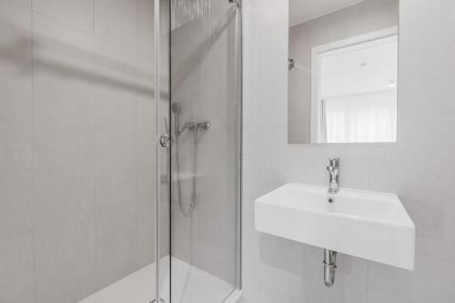 a white bathroom with a sink and a shower at Prenočišča AUTUR in Tolmin