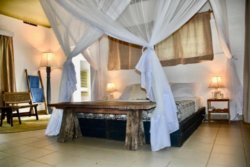 a bedroom with a canopy bed with a wooden table at Salty's Kitesurf Village in Kilifi
