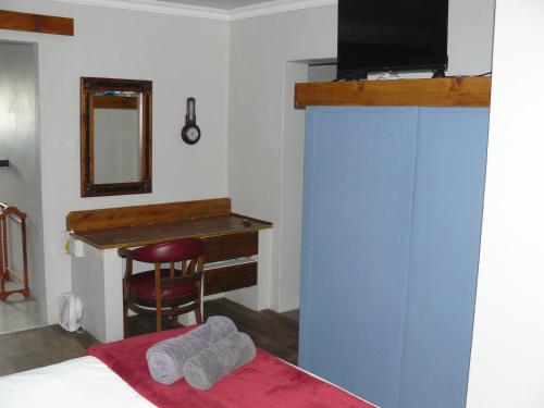 a bedroom with a bed and a desk with a television at House of 2 Oceans in Agulhas