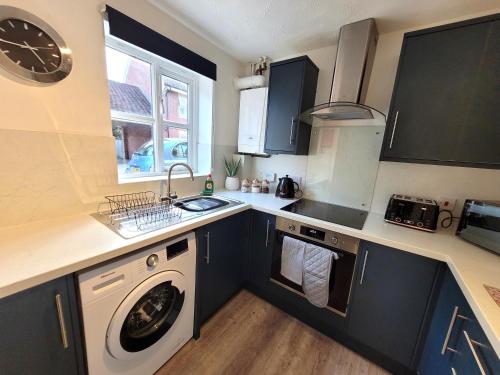 a kitchen with a washing machine and a sink at Hythe House - Stylish Stay for Families & Groups by Catchpole Stays in Colchester