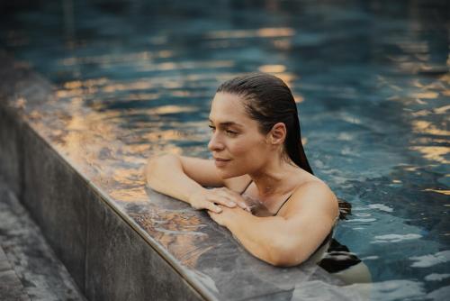 a woman is sitting in a swimming pool at Taubers Bio Vitalhotel in Chienes