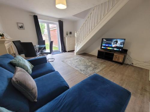 a living room with a blue couch and a tv at Hythe House - Stylish Stay for Families & Groups by Catchpole Stays in Colchester