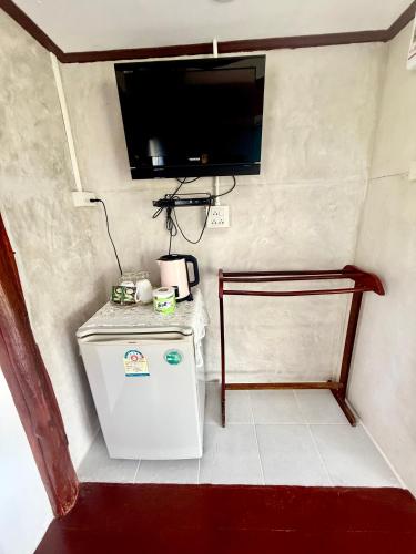 a small refrigerator in a room with a tv on the wall at Wandee Resort Bankrut in Ban Krut