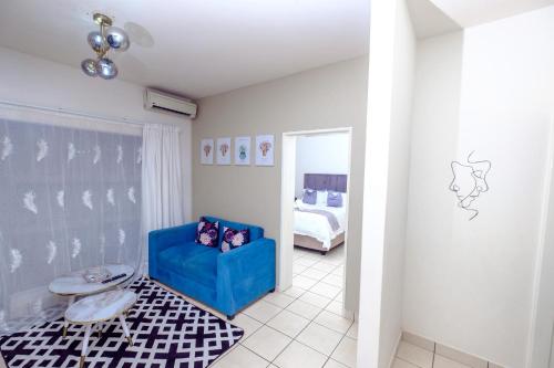 a living room with a blue chair and a bed at River flow apartment in Manzini