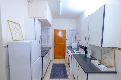 a kitchen with white appliances and a wooden door at River flow apartment in Manzini