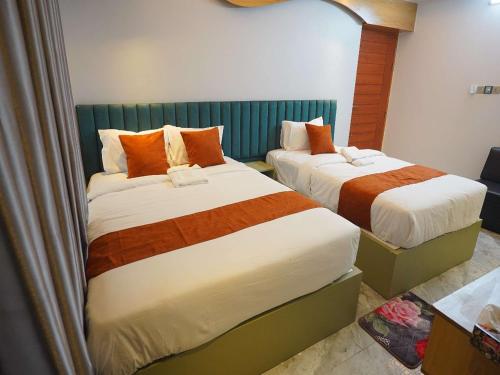 a bedroom with two beds with orange and white sheets at Hotel The Light Park in Chittagong