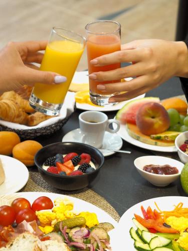 a table with plates of food and two glasses of juice at Van der Valk Hotel Paris CDG Airport in Roissy-en-France