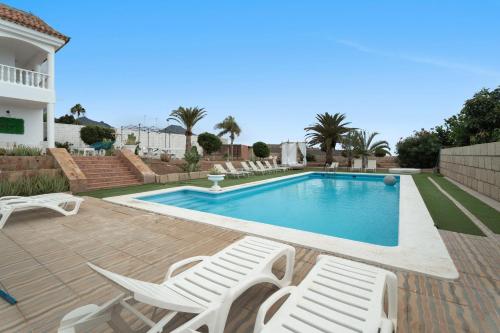 a swimming pool with chaise lounge chairs and a house at Villa Luxury el Mirador in Adeje