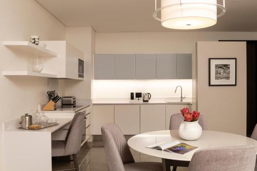 a kitchen with a table and chairs and a white kitchen at The Leonardo in Johannesburg