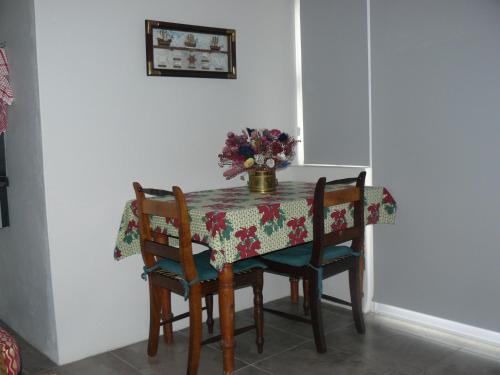 a table with chairs and a vase of flowers on it at House of 2 Oceans in Agulhas