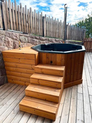 a hot tub sitting on a wooden deck with stairs at Parliflhof Apt Langfenn in Meltina