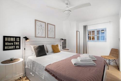 Un dormitorio blanco con una cama y una silla. en Casa Amarela, en Tavira