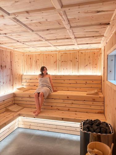 a woman sitting in a wooden sauna at Parliflhof Apt Langfenn in Meltina