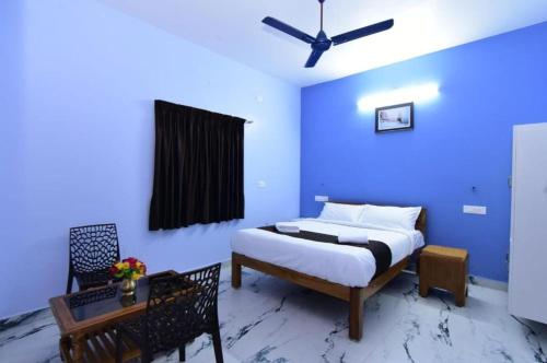 a bedroom with a bed and a blue wall at Thilo Guest House Auroville in Auroville