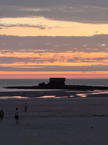 a group of people walking on the beach at sunset at L'appartement cosy du Portel in Le Portel