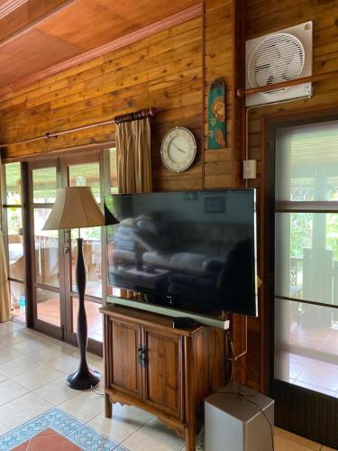 a living room with a flat screen tv on a wooden wall at Baan Laem Noi Villa's in Mae Nam
