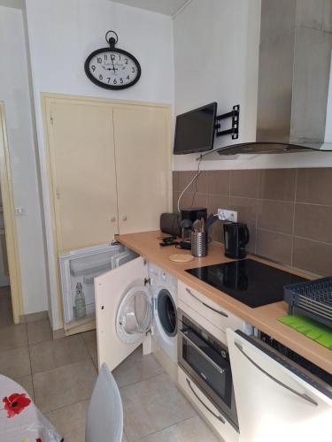 una cucina con lavatrice e orologio sul muro di Appartement tout équipé - Le Beau Site ad Aix-les-Bains