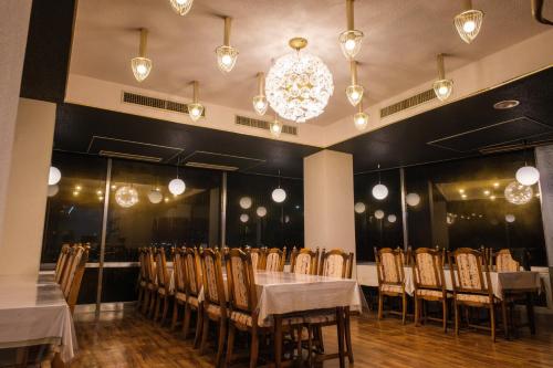 a dining room with tables and chairs and a chandelier at MUST WIN Hotel in Takasaki