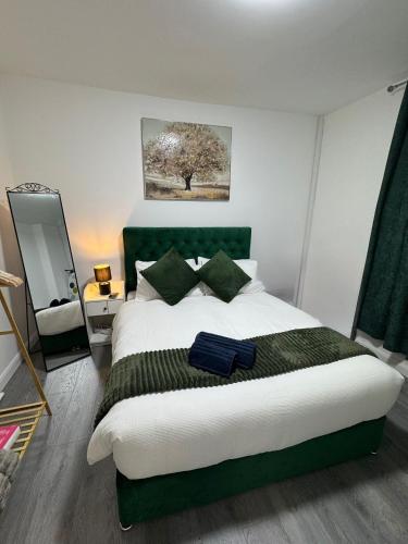a bedroom with a large bed with a green headboard at City Escape Stylish 4 bedroom house in Nottingham Sleep 9 in Nottingham