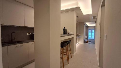 a kitchen with white cabinets and a bar with stools at Teatro Romano Exclusive Suites in Trieste
