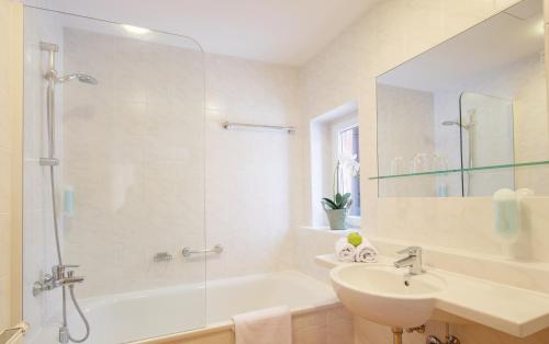 a white bathroom with a sink and a shower at Hotel Der Waldhof in Zell am See