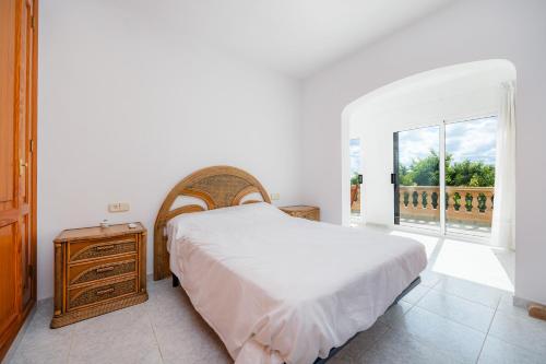 a white bedroom with a bed and a window at Ses Tanquetes in Pina
