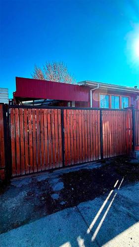 a red fence in front of a building at A paso del centro, mini cabaña cómoda in Puerto Natales