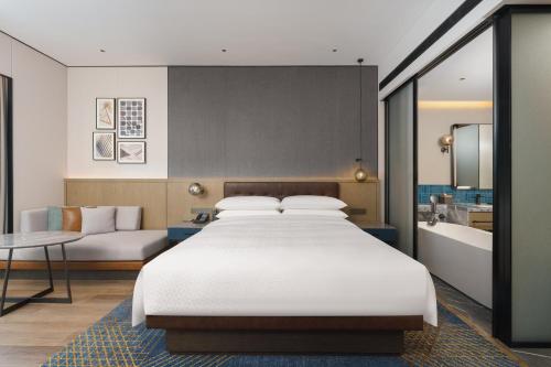 a bedroom with a large bed and a bath tub at Four Points by Sheraton Dalian Donggang in Dalian