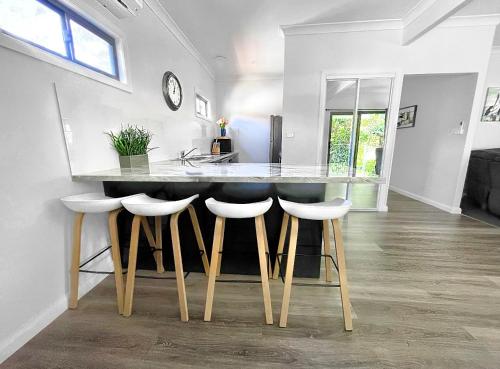 a kitchen with a counter with four stools around it at Seaside Escape - 5 BR 2 Kitchens in Port Macquarie