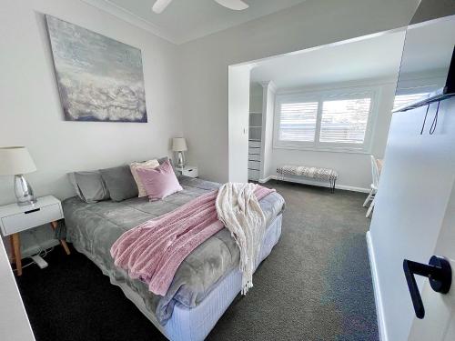 a bedroom with a bed with a pink blanket on it at Seaside Escape - 5 BR 2 Kitchens in Port Macquarie