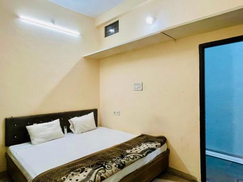 a small bedroom with a bed with white sheets and pillows at Hotel Maa Aarti Palace in Ujjain