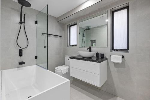 a white bathroom with a sink and a shower at Modern 3BR Glebe Home with Terrace & Garage for 8 in Sydney