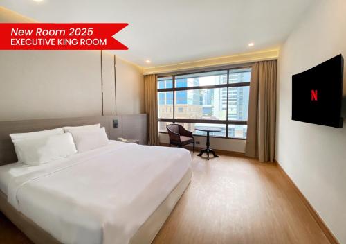 a bedroom with a large white bed and a window at Pinnacle Lumpinee Park Hotel in Bangkok